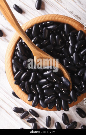 Les haricots noirs dans un bol en bois sur la table close-up vertical Vue de dessus. Banque D'Images