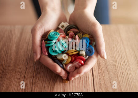 Les mains pleines de boutons colorés