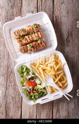 Fast food : Brochettes, frites et salade fraîche dans le plateau sur la table. vertical vue d'en haut Banque D'Images