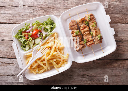 Fast food : Brochettes, frites et salade fraîche dans le plateau sur la table horizontale vue du dessus. Banque D'Images