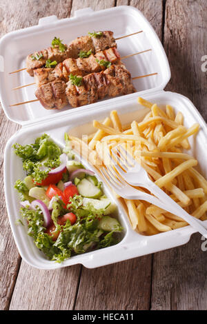 Boîte à lunch : Brochettes, frites et salade fraîche dans le bac sur la table. vertical Banque D'Images