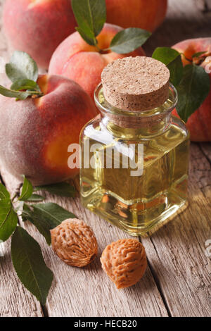 Peach parfumés de l'huile dans une bouteille en verre sur une table close-up vertical. Banque D'Images