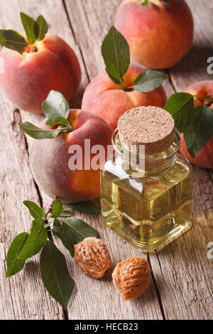 L'huile naturelle de peach stone dans une bouteille en verre sur une table close-up vertical. Banque D'Images