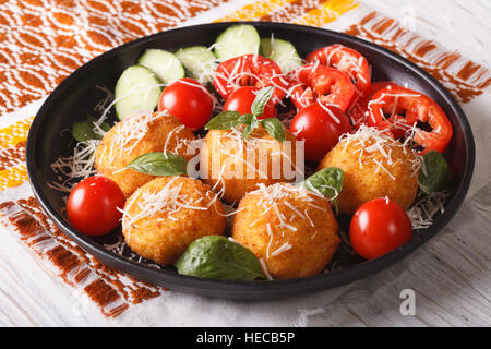 Boules de riz arancini italien avec du fromage et des légumes frais sur la plaque horizontale de près. Banque D'Images