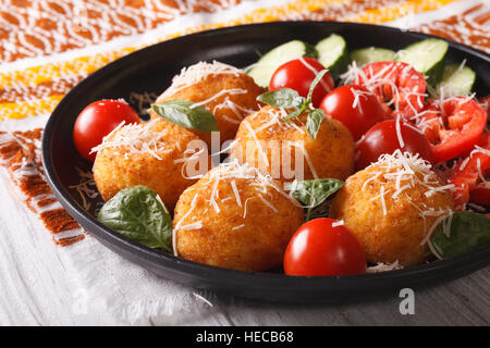 Boules de riz arancini frits et salade de légumes frais sur une plaque horizontale. Banque D'Images