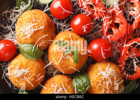 Contexte : La nourriture italienne arancini frits boulettes de riz avec une salade de légumes frais macro. vue horizontale d'en haut Banque D'Images