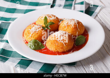 Délicieux arancini frits boulettes de riz avec de la sauce tomate sur la table horizontale. Banque D'Images