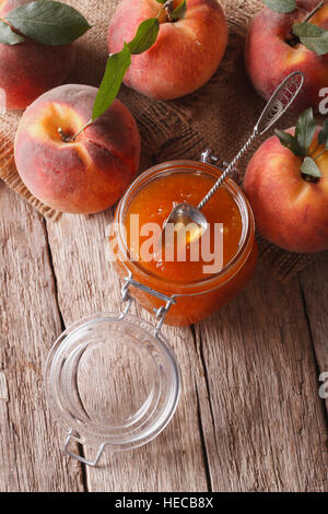 Confiture de pêches fraîches dans un bocal en verre fermer vers le haut sur la table. vertical vue d'en haut Banque D'Images