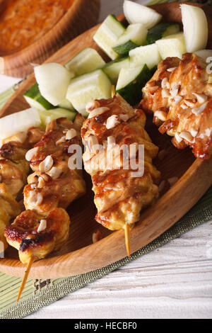 Satay de poulet saupoudré d'arachides rôties sur une assiette. La verticale Banque D'Images