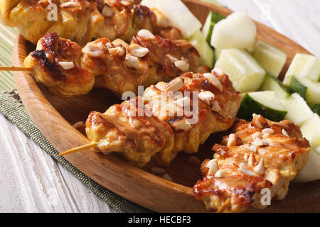 Satay de poulet arrosé avec des cacahuètes grillées sur une plaque horizontale. Banque D'Images