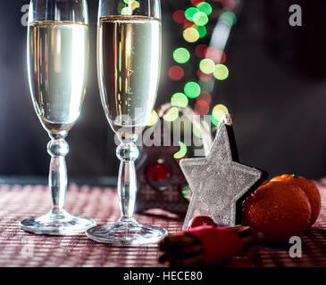 La veille du Nouvel An. Image de deux wineglasses de champagne, en bois et de décoration étoile arbre généalogique, la cannelle et les mandarines sur l'arrière-plan des lumières bokeh. Banque D'Images