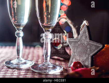 La veille du Nouvel An. Image de deux wineglasses de champagne, en bois et de décoration étoile arbre généalogique, la cannelle et les mandarines sur l'arrière-plan des lumières bokeh. Banque D'Images