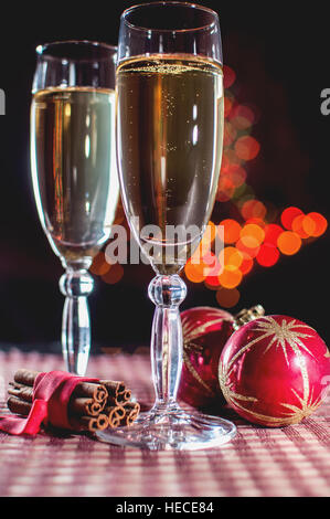 La veille du Nouvel An. Image de deux wineglasses de champagne, deux boules de Noël rouge et cannelle sur l'arrière-plan des lumières bokeh. Clé faible. Focu sélective Banque D'Images