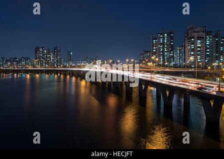 Allumé résidentiel le long de la rivière Han et le trafic sur un pont à Séoul, Corée du Sud, de nuit. Banque D'Images