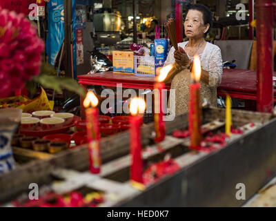 Bangkok, Bangkok, Thaïlande. Dec 21, 2016. Une femme prie dans un temple chinois au marché de rat, Chareon un marché de la classe ouvrière dans la section de Thonburi Bangkok. Le salaire minimum en Thaïlande, fixé à 300THB (environ 8.50US) par jour en 2013, devrait augmenter le 1er janvier 2017. Le 300THB salaire minimum national a été adopté par le gouvernement de Yingluck Shinawatra, en 2013. Les intérêts des entreprises et de l'armée contre le salaire minimum, l'appeler un ''programme populiste''. Yingluck a été destitué par un coup d'État militaire en 2014 et le salaire minimum a été laissé expirer en 2015. Cette année, le gouvernement militaire Banque D'Images