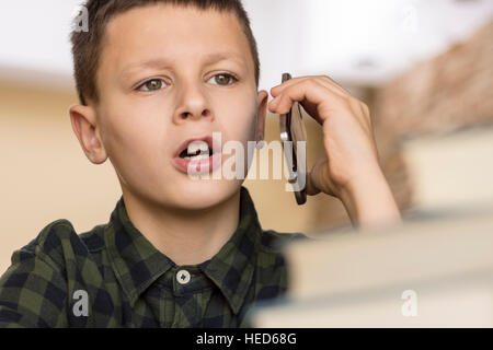 Young Boy Talking on Cell Phone at home. Parler de téléphone mobile Concept. Banque D'Images
