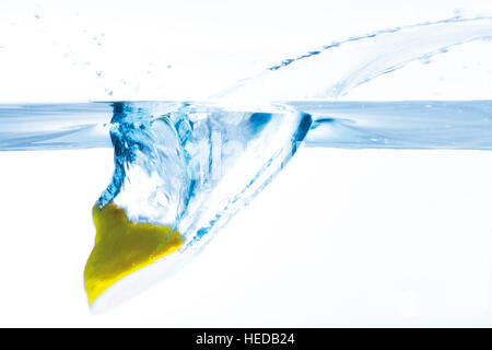 Un demi citron plongeant dans l'eau Banque D'Images