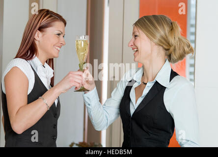 Deux jeunes femmes heureux de boire du vin mousseux ensemble Banque D'Images