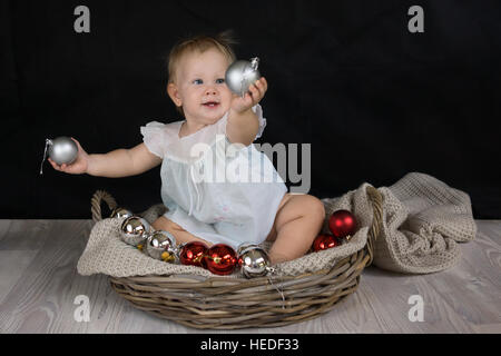 Baby Girl holding et jouer avec des boules de Noël Banque D'Images