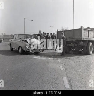 1965, historique, se trouvant au milieu d'une route à la suite d'un accident automobile où l'avant de l'automobile a frappé l'arrière d'un camion. Banque D'Images