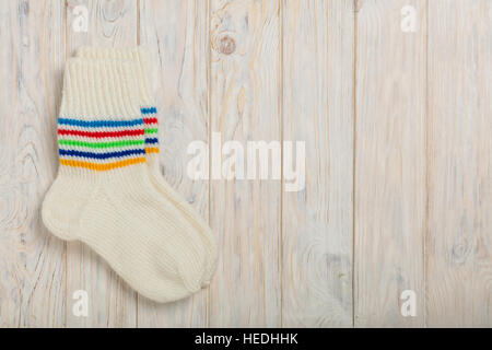 Chaussettes de laine tricotées couleur blanche sur fond de bois clair. Banque D'Images