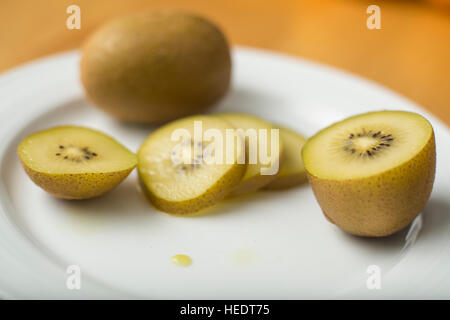 Tranches de kiwi doré sur une plaque blanche Banque D'Images