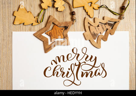 Les jouets en bois sur fond blanc avec texte Joyeux Noël. Lettrage calligraphie Banque D'Images