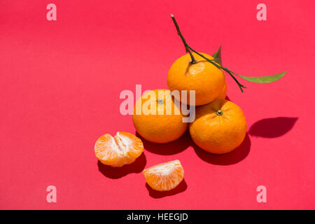 Mandarine avec des feuilles sur fond rouge Banque D'Images