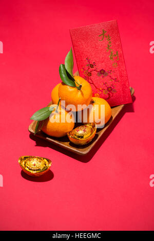 Nouvelle année lunaire chinoise. Orange mandarine avec angbao sur fond rouge Banque D'Images