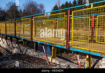 Pont métallique de la section U et en métal et fil tissé, peint en bleu vif, jaune et rouge, de l'autre côté de la baie sur le lac Banque D'Images