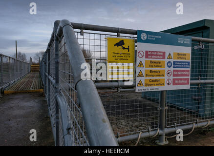 Vannes d'équipement électrique et de multiples signes vu par une rivière, à proximité d'un canal de navigation de plaisance. Banque D'Images