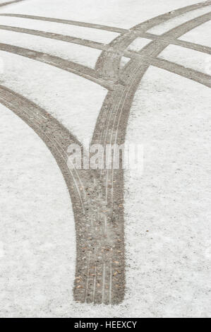 Les traces de pneus / les marques dans la neige fraîche sur une route pavée. Banque D'Images