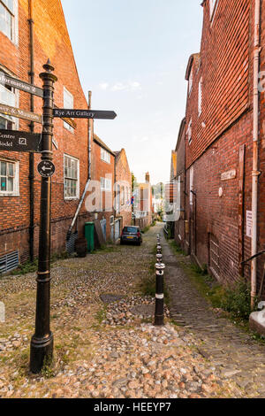 Centre historique de la vieille ville anglaise de seigle. La colline de conduit, étroites et pavées lane, High Street, à bas le long. Inscrivez-touristiques en premier plan. Banque D'Images