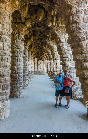 Deux touristes, un homme et sa femme, à pied le long d'une ligne de voûtes en pierre dans le parc Grüell conçue par Gaudí à Barcelone, Espagne. Banque D'Images