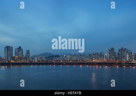 Vue d'un quartier résidentiel allumé et le pont le long de la rivière Han à Séoul, Corée du Sud, de nuit. Copier l'espace. Banque D'Images