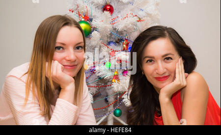 Deux belles filles couché à côté d'un arbre de Noël Banque D'Images