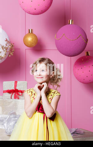 Valentine pour rendre vos doigts. Jolie petite fille de 6 ans dans une robe jaune. Bébé en rose quartz salle décorée maison de vacances. Banque D'Images