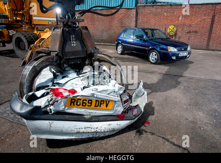 Mâchoires de la mort - un crushedVauxhall 442 dans la griffe d'un parc à ferrailles lors d'une grue, une cour breakers Ford Fiesta attend le même Banque D'Images