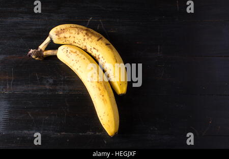 Deux bananes mûres sur fond de bois foncé Banque D'Images