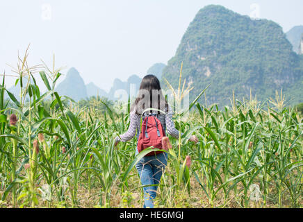 Fille qui marche dans un champ de maïs avec des paysages karstiques Banque D'Images