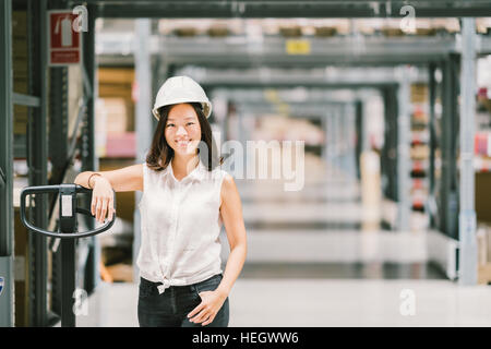 Beautiful Young Asian woman smiling technicien ou ingénieur, un entrepôt ou une usine d'arrière-plan flou, l'industrie ou concept logistique, with copy space Banque D'Images