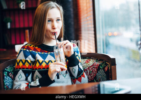 Photo d'une femme boire du jus d'une fenêtre Banque D'Images