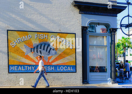 Homme marche par Amen Street Fish & Raw Bar restaurant sur la baie East de l'arty avec peinture murale au centre-ville historique de Charleston, SC Banque D'Images