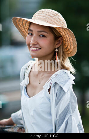 Heureux, belle fille japonaise portant un chapeau de paille et smiling at the camera Banque D'Images