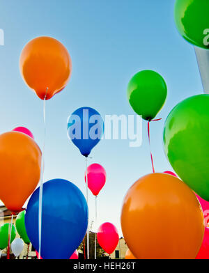 De nombreux ballons colorés lancé à partir de la les enfants heureux volant dans le ciel bleu Banque D'Images