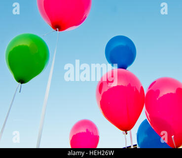 De nombreux ballons colorés lancé à partir de la les enfants heureux volant dans le ciel bleu Banque D'Images