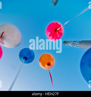 De nombreux ballons colorés lancé à partir de la les enfants heureux volant dans le ciel bleu Banque D'Images