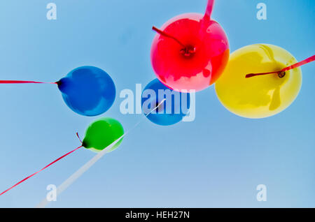 De nombreux ballons colorés lancé à partir de la les enfants heureux volant dans le ciel bleu Banque D'Images