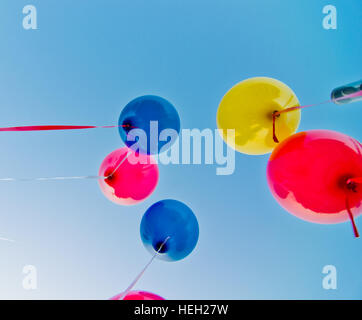 De nombreux ballons colorés lancé à partir de la les enfants heureux volant dans le ciel bleu Banque D'Images