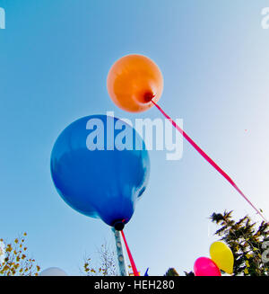 De nombreux ballons colorés lancé à partir de la les enfants heureux volant dans le ciel bleu Banque D'Images